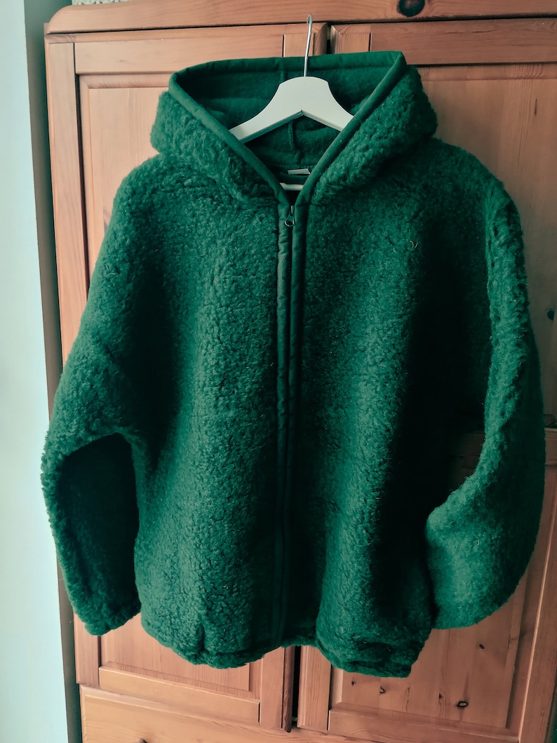 May include: A dark green hooded fleece jacket with a zip closure.