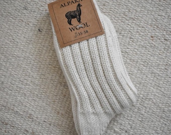 May include: White alpaca wool socks with a brown tag that says "Alpaca Wool" and has a picture of an alpaca. The tag also says "35-38".