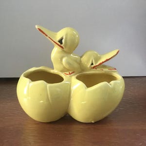 Peut inclure: Un pot en céramique jaune avec deux figurines de canards sur le dessus. Le pot a trois compartiments séparés pour les plantes.