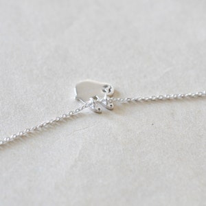 K&ouml;nnte beinhalten: Eine zarte Silberkette mit einem kleinen, polierten Anh&auml;nger in Form eines stilisierten Eisb&auml;ren. Der B&auml;renanh&auml;nger ist mit einer feinen Kette verbunden, wodurch ein minimalistisches und elegantes Schmuckst&uuml;ck entsteht. Die Kette wird auf neutralem Hintergrund pr&auml;sentiert.