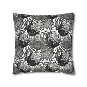 May include: Black and white throw pillow with a repeating pattern of protea flowers.