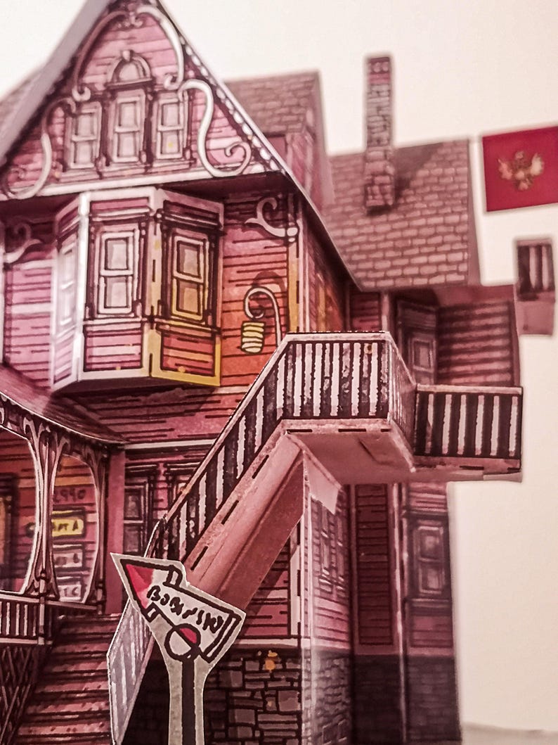 May include: A pink paper model of a house with a white and black striped railing and a red and white sign that says "WARNING".
