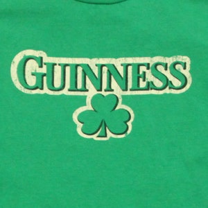May include: Green t-shirt with a white vintage-style "GUINNESS" logo and a green shamrock.