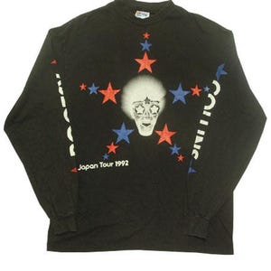 May include: A black long-sleeve t-shirt featuring a central graphic of a face with star-shaped eyes surrounded by red and blue stars. The text "Japan Tour 1992" is printed below the graphic, and "BOOTSY COLLINS" is printed down the sleeves.