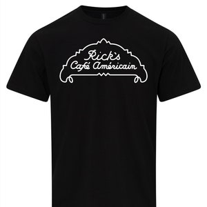 May include: Black t-shirt with a white graphic of a cafe sign that says "Rick's Café Américain".