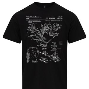 May include: Black t-shirt featuring a white schematic diagram of a 3D printer, with the text "United States Patent" and patent information. The diagram includes various components and labels, with the patent date of Jan. 9, 1992.