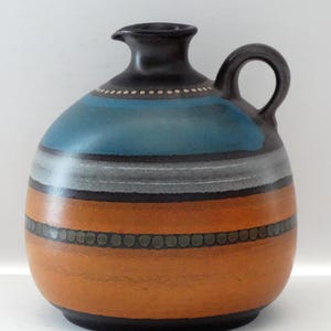 May include: A white ceramic mug with a black handle and the text "But First, Coffee" in a handwritten style. The mug is on a white surface. The mug is approximately 4 inches tall.