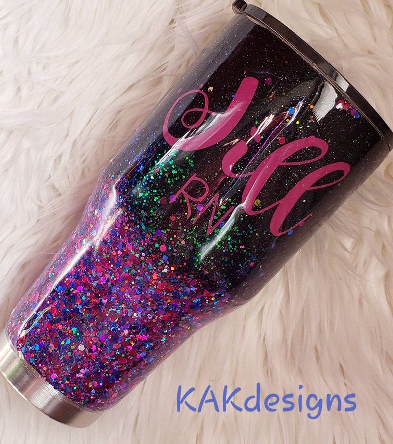 May include: A black and purple glitter tumbler with a pink design that says "Jill RN".