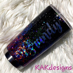 May include: A black and iridescent glitter tumbler with the name "Brandy" written in silver lettering.