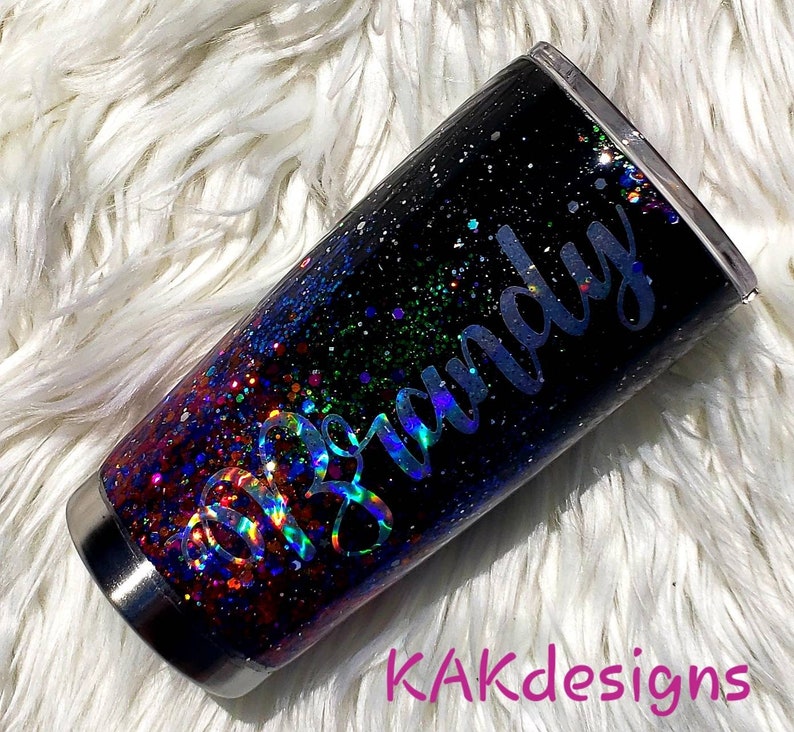 May include: A black and iridescent glitter tumbler with the name "Brandy" written in silver lettering.