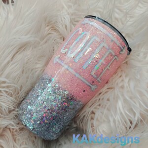 Puede incluir: Un vaso de glitter rosa y plateado con la palabra "COFFEE" escrita en blanco en la parte rosa. El vaso tiene una tapa negra.