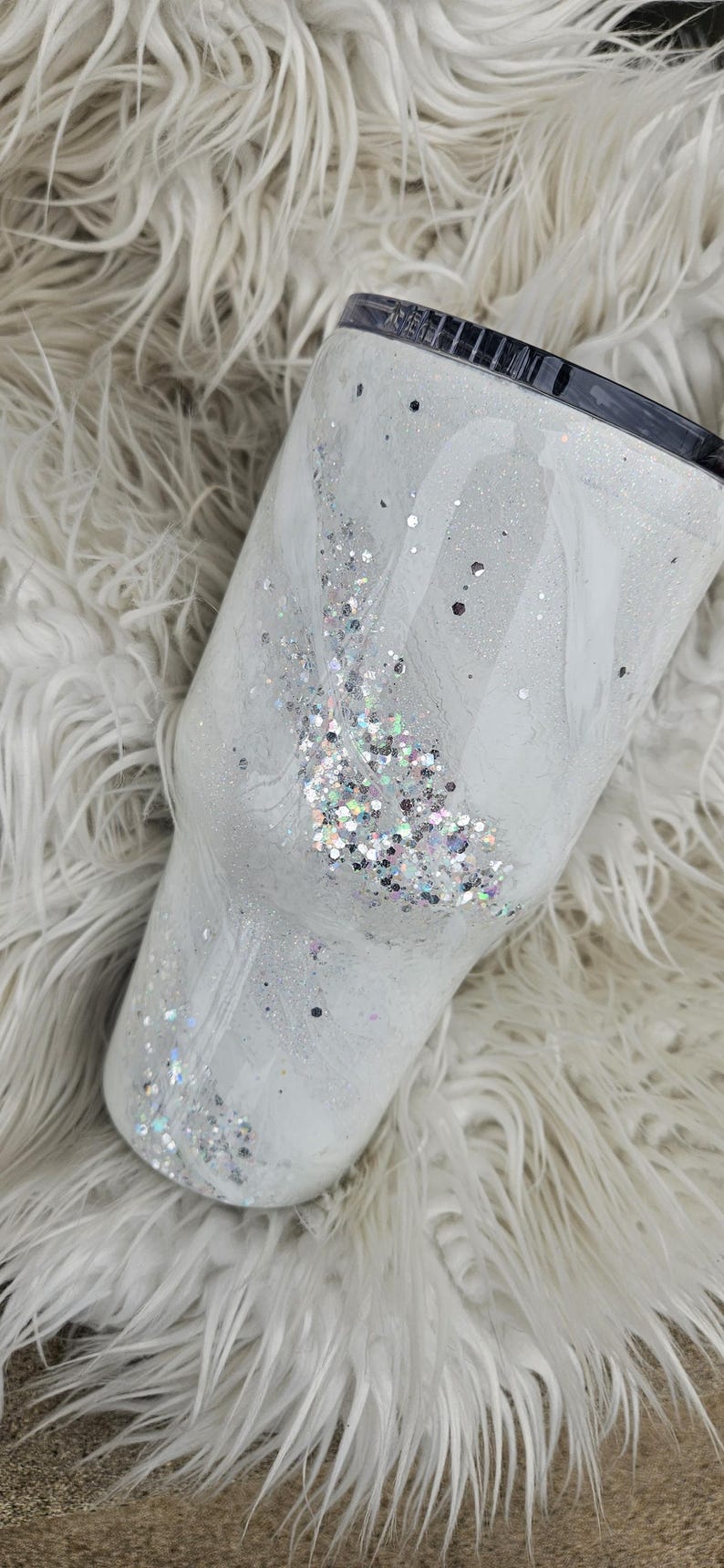 May include: White tumbler with a swirl design and silver glitter. The tumbler has a black lid.