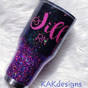 May include: A black and pink glitter tumbler with the name "Jill RN" written on it.