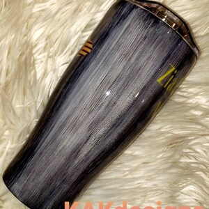 May include: A black and white stainless steel tumbler with a gold glitter finish. The tumbler has a brushed metal look and a gold stripe design. The text "Zita" is written in gold on the side of the tumbler.