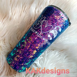 May include: A purple and blue glitter tumbler with a leopard print design. The tumbler has the text "Peace Love Momlife" with a peace sign and heart.
