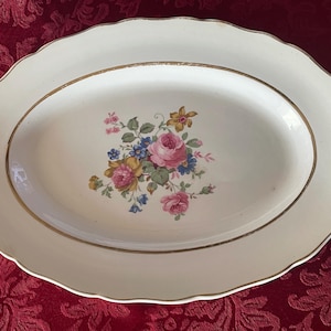 Puede incluir: Plato ovalado blanco para servir con borde dorado y diseño floral en tonos rosa, amarillo y azul.