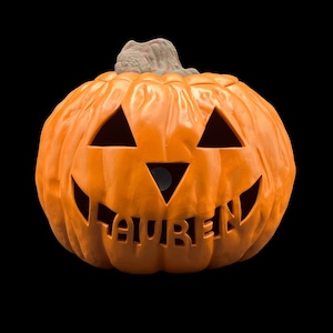 May include: Orange plastic jack-o'-lantern with a carved face and the name "Lauren" written inside.