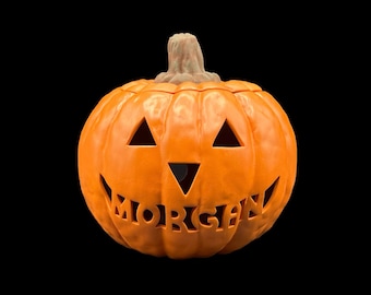 May include: Orange ceramic pumpkin with a carved jack-o'-lantern face and the name "MORGAN" carved into the bottom.