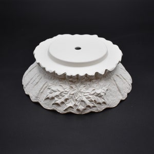 May include: White ceramic Christmas tree base with a scalloped edge and a holly leaf design.