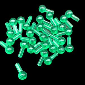 May include: A pile of green plastic Christmas light bulbs with a clear, translucent finish. The bulbs have a small, round shape and a short, straight stem.