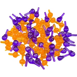 Puede incluir: Un montón grande de cubiertas de bombillas de plástico de color morado y naranja con forma de calavera. Las cubiertas de bombillas son para usar en luces de Navidad.