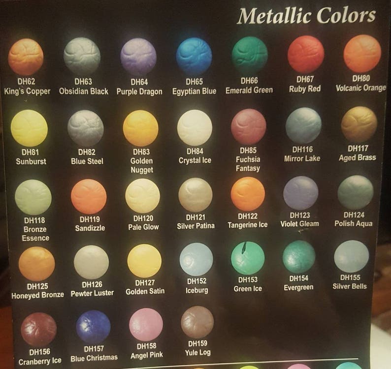 May include: A chart of metallic paint colors with names and corresponding color swatches. The colors include King's Copper, Obsidian Black, Purple Dragon, Egyptian Blue, Emerald Green, Ruby Red, Volcanic Orange, Sunburst, Blue Steel, Golden Nugget, Crystal Ice, Fuchsia Fantasy, Mirror Lake, Aged Brass, Bronze Essence, Sandizzle, Pale Glow, Silver Patina, Tangerine Ice, Violet Gleam, Polish Aqua, Honeyed Bronze, Pewter Luster, Golden Satin, Iceburg, Green Ice, Evergreen, Silver Bells, Cranberry Ice, Blue Christmas, Angel Pink, and Yule Log.