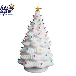 Può includere: Un albero di Natale in ceramica bianca con luci colorate e una stella dorata in cima. L'albero ha un design classico con una superficie strutturata e una base rotonda. Il testo "Lights Up Accessories Included" è nell'angolo in alto a sinistra.