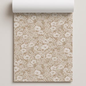 May include: A roll of wallpaper featuring a dense, repeating pattern of white flowers and small blossoms set against a solid tan background. The design displays a variety of floral shapes and foliage, creating a continuous botanical print.