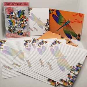 May include: Rainbow Hibiscus stationery set with a dragonfly design. The set includes letter writing paper, envelopes, and a card with the text "Fly Free".
