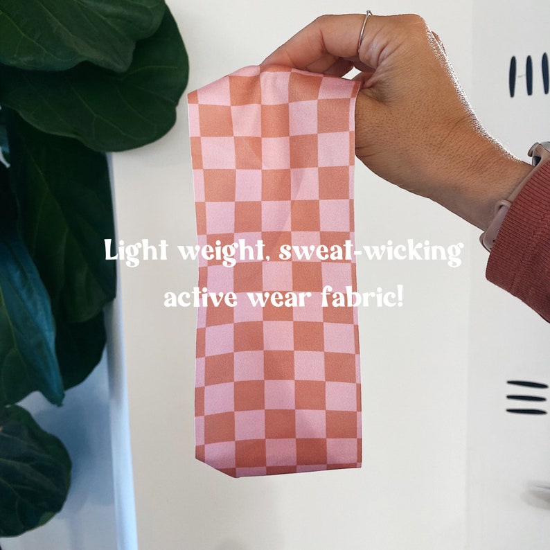 May include: A pink and brown checkered headband made from a lightweight, sweat-wicking activewear fabric. "Light weight, sweat-wicking active wear fabric!" is written in white text below the headband.