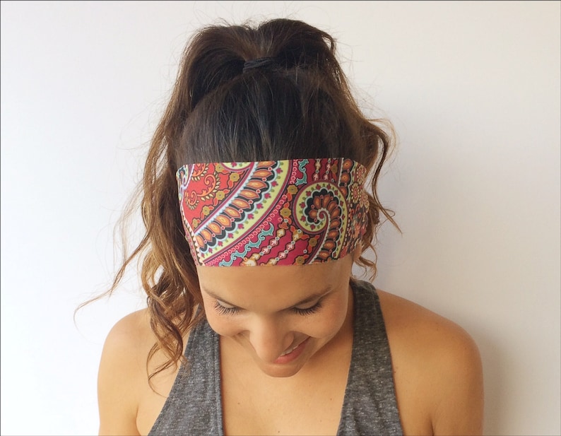 May include: A woman with brown hair wearing a red, pink, and blue paisley patterned headband.
