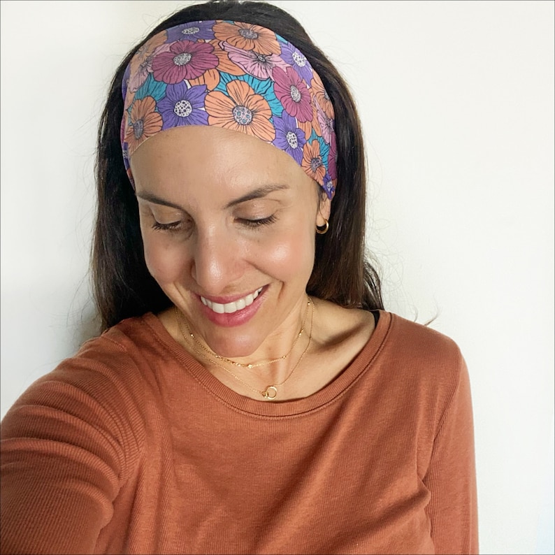 May include: A woman wearing a brown long-sleeved shirt with a floral headband. The headband has a pattern of pink, orange, purple, and blue flowers.