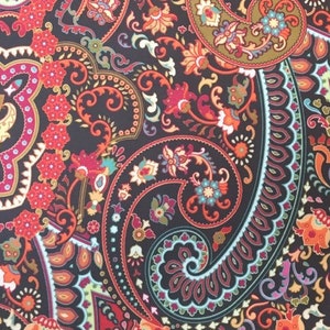 May include: A black fabric with a paisley pattern in shades of red, orange, yellow, green, blue, and purple. The pattern is intricate and detailed, with a variety of shapes and sizes.