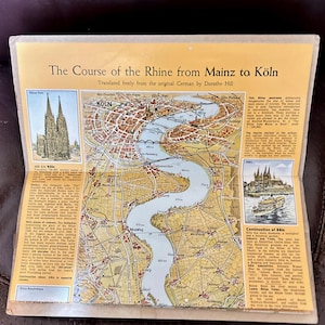 May include: A vintage map titled "The Course of the Rhine from Mainz to Köln," translated from German. The map features illustrations of Cologne Cathedral and a riverboat, with detailed cartography of the Rhine River.