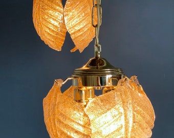May include: A gold-toned chandelier with two tiers of frosted glass leaf-shaped shades. The leaves have a textured surface and are illuminated from within.