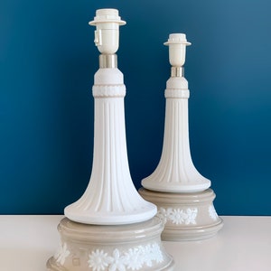 May include: Two white ceramic table lamps with a beige base. The bases have a white floral design.