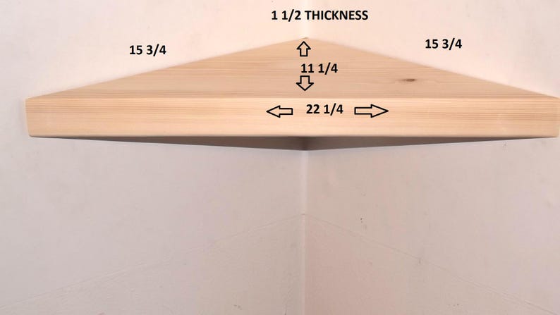 May include: A light-colored wooden corner shelf with a triangular shape. The shelf features printed dimensions: 1 1/2 thickness, 15 3/4 sides, 11 1/4 depth, and 22 1/4 front width. The shelf is mounted in a corner against a plain white wall.