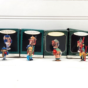 May include: Six Hallmark Keepsake Ornament nutcracker figurines in individual dark green boxes. Each small wooden-style figure features distinct colorful uniforms, hats, and accessories, including skis, musical instruments, and various seasonal items.