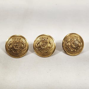 May include: Three circular gold-toned metal buttons featuring a raised relief design of the USMS emblem. Each button displays a central anchor surrounded by a wreath and the letters USMS at the top, with a polished finish and a slightly domed surface.