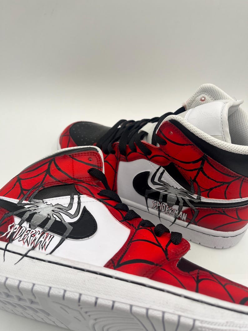 Puede incluir: Par de zapatillas altas con tem&aacute;tica de Spider-Man. Los zapatos presentan una combinaci&oacute;n de colores rojo y negro con un dise&ntilde;o de telara&ntilde;a y la palabra "SPIDERMAN" impresa en el lateral. Las suelas son blancas.