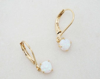May include: A pair of gold earrings with white opal stones. The earrings have a lever back closure.
