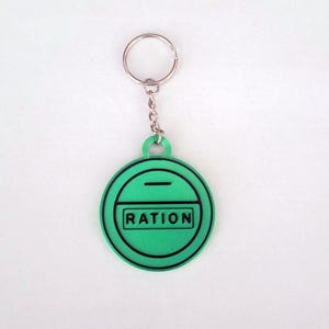 May include: A green keyring with a silver ring and a round tag that says "RATION" in black letters.