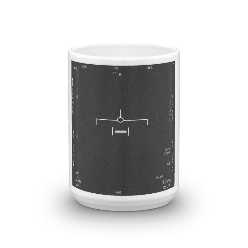 May include: A white ceramic mug featuring a black and white image of an aircraft cockpit display. The display shows the plane's altitude, heading, and other flight information. The text on the display reads "IR 4&deg; R", "RTCL", "LIDR", "AN OK", "19990", and "OCLTR".