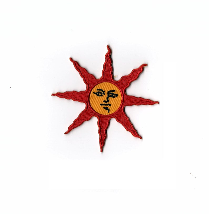 May include: A red embroidered patch with a stylized sun with a face. The sun is yellow with a black face and is surrounded by 10 red points.