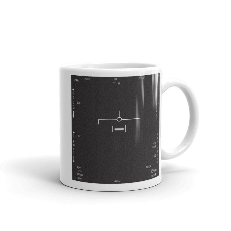 May include: White ceramic mug featuring a black and white image of a radar screen. The screen displays the text "NAR", "OP", "IR", "RTCL", "ZOOM", "2.0", "ADV", "252", "MO1S", "WHT", "4245", "1990", "OCTY".