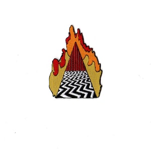 Puede incluir: Un patrón de zigzag blanco y negro con un triángulo rojo en la parte superior, todo envuelto en llamas amarillas y naranjas.