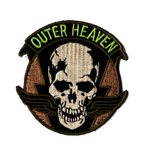 May include: A green, brown, and white embroidered patch with a skull and crossbones and the text "OUTER HEAVEN" in green.
