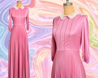 Könnte beinhalten: Ein rosafarbenes Maxikleid mit einem weißen Spitzenkragen und langen Ärmeln. Das Kleid ist plissiert und hat einen taillierten Oberteil.