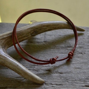 Peut inclure: Un collier simple en cordon de cuir marron avec une fermeture nouée.