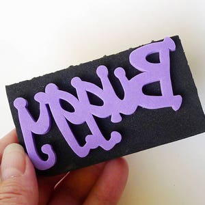 May include: Purple foam letters spelling "Happy" on a black foam sheet.